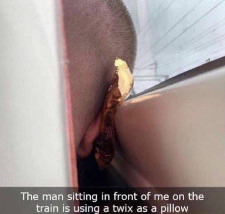 The man sitting in front of me on the train is using a twix as a pillow