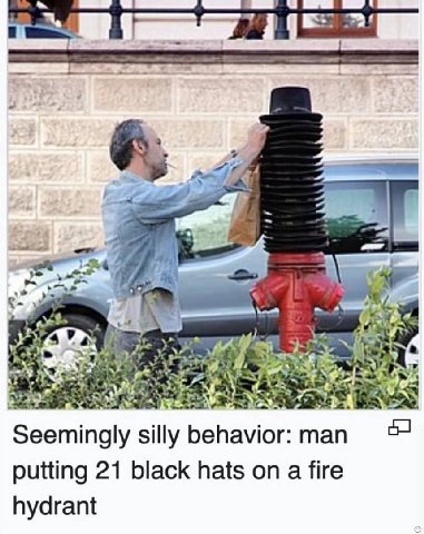 Seemingly silly behavior: man putting 21 black hats on a fire hydrant
