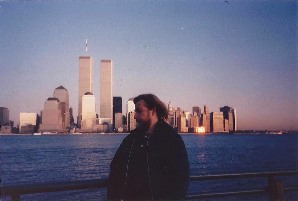 Например, Пахом на фонe WTC.

Фиолетовый закат над Гудзоном, зерно на плёнке. На фоне застыли две башни Всемирного торгового центра как неоновые обелиски уходящей эпохи.
Сквозь этот глитч матрицы смот